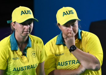 Two Australian athletes in bright yellow uniforms stand side by side, looking focused during a competition.