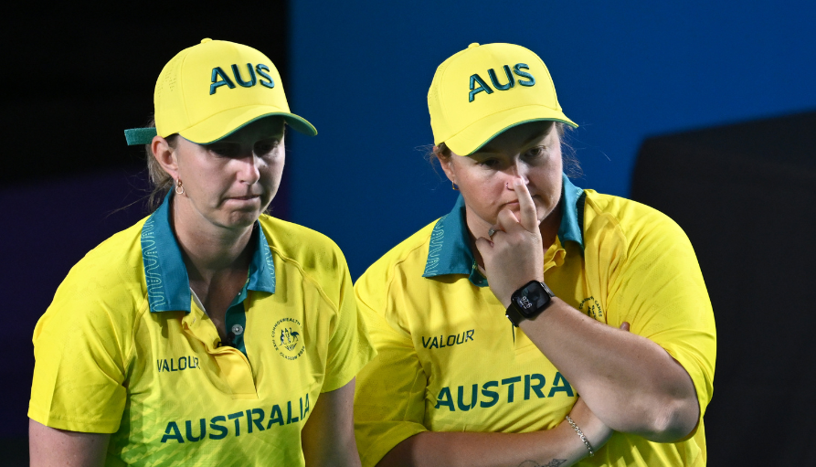 Two Australian athletes in bright yellow uniforms stand side by side, looking focused during a competition.