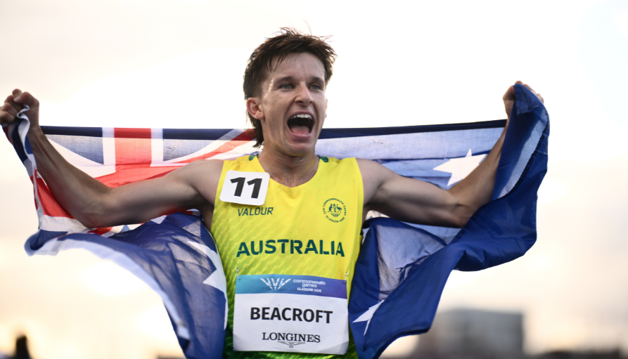 Australian sprinter Beacroft finishes race, arms raised, draped in the Australian flag.