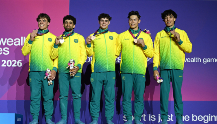 Five athletes in yellow‑green outfits on a podium, each with a medal and a mascot against a purple backdrop.