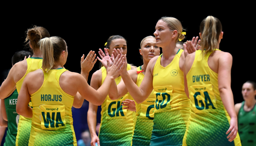 Group of female teammates in yellow-green uniforms high-fiving on an indoor court.