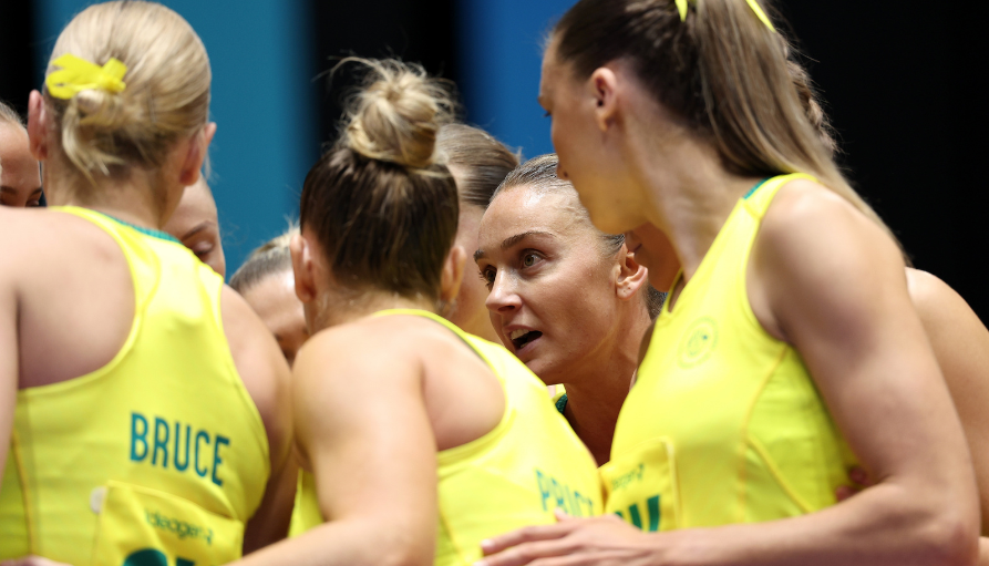 Group of female athletes in neon yellow jerseys huddling together during a game, one player’s back reads 'BRUCE' and they look focused.